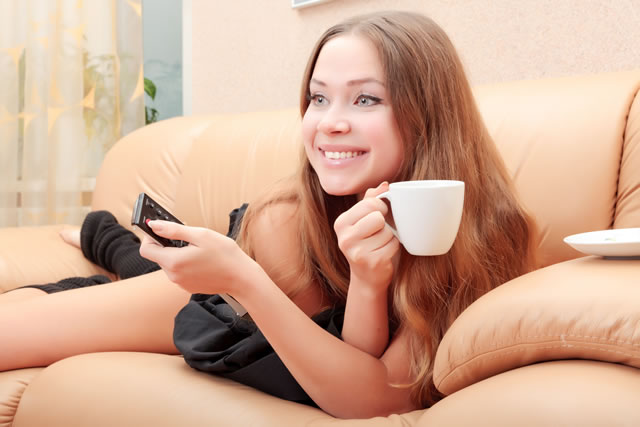 ソファーの上でコーヒーを飲む女性