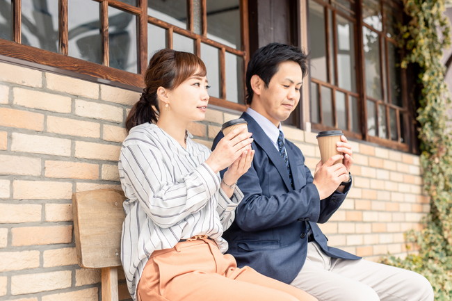 ベンチでコーヒーを飲んでいる男女